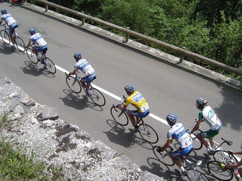 A group of racing cyclists in a line drafting along a road