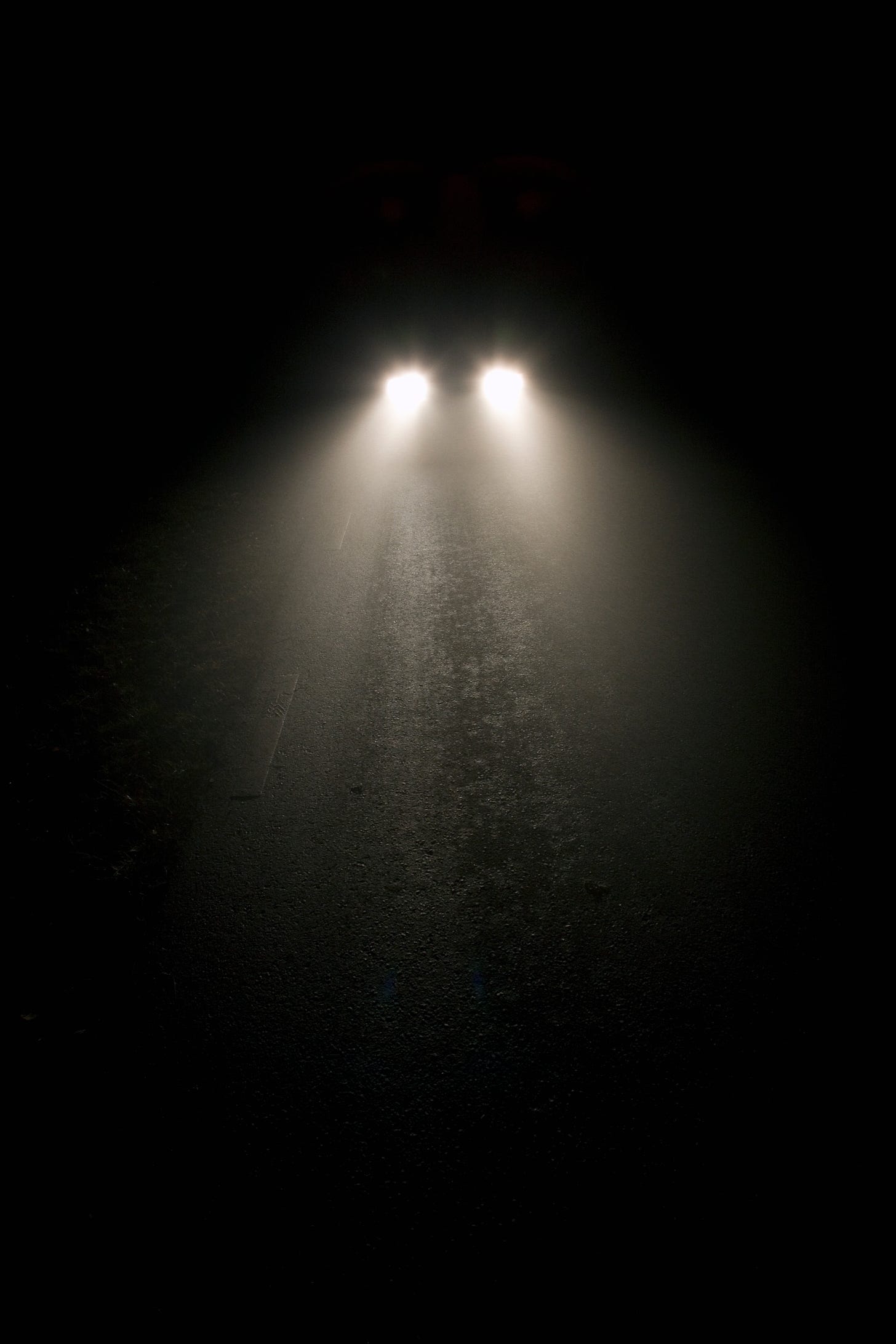 Car headlights in light fog at night
