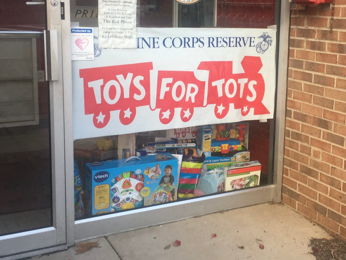 Toys for Tots sign in window with toys below