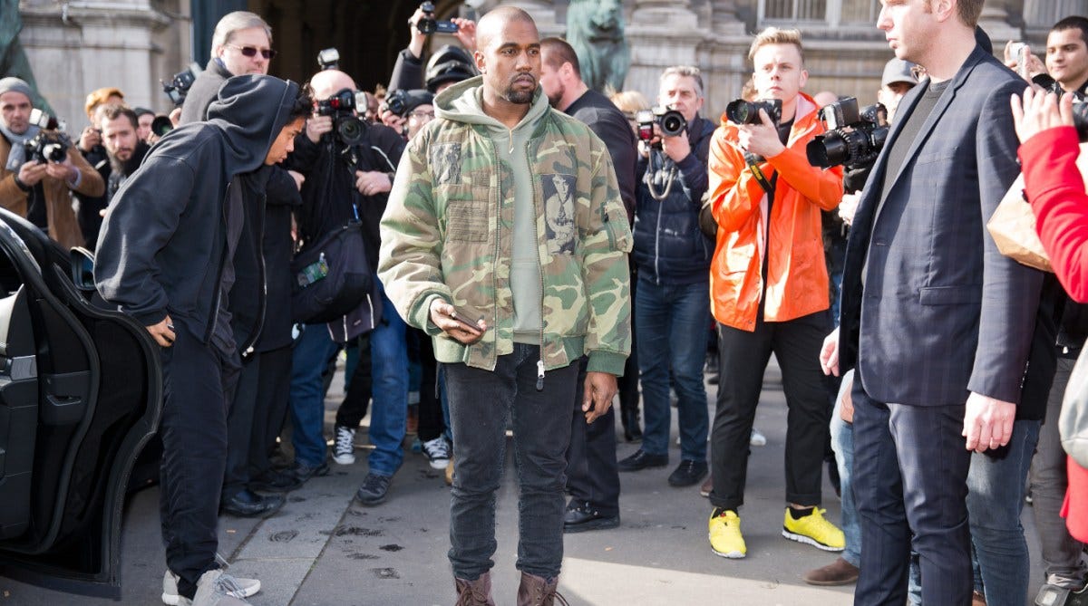 Kanye West's new private Christian school Donda Academy is surrounded by red flags | Kanye West posing for photographers in front of the Dries van noten fashion show