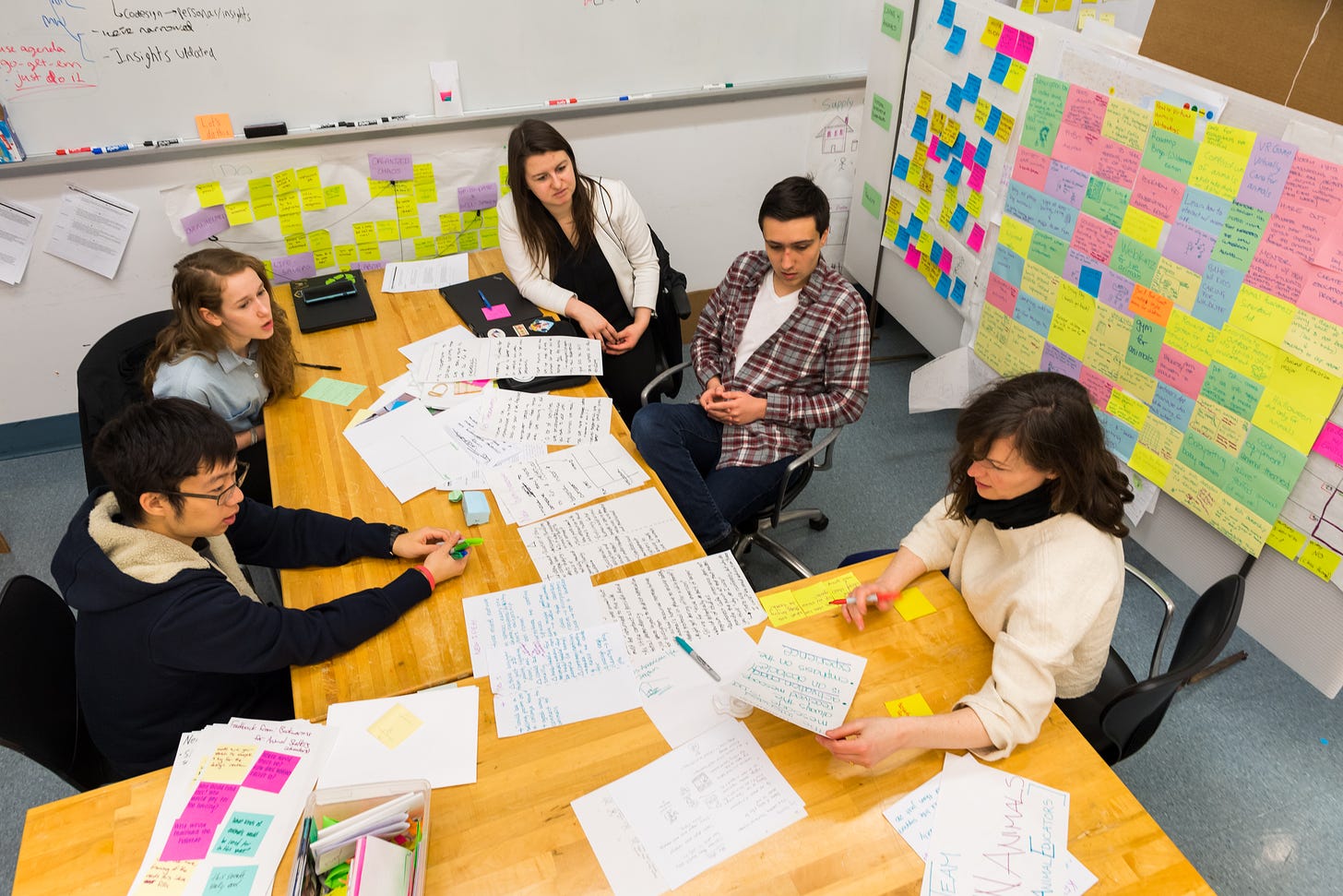 A group of four students and I sit around a set of tables and talk through all kinds of design ephemera in the design studio: index cards, sticky notes, sketches and text and more.