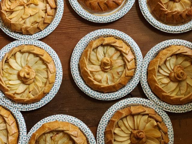 Pies with curled edges and fanned apple slices on plates