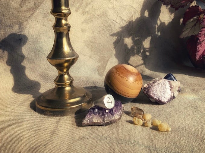 A still life featuring a silver signet ring with the glyph of Jupiter sitting on an amethyst crystal cluster.