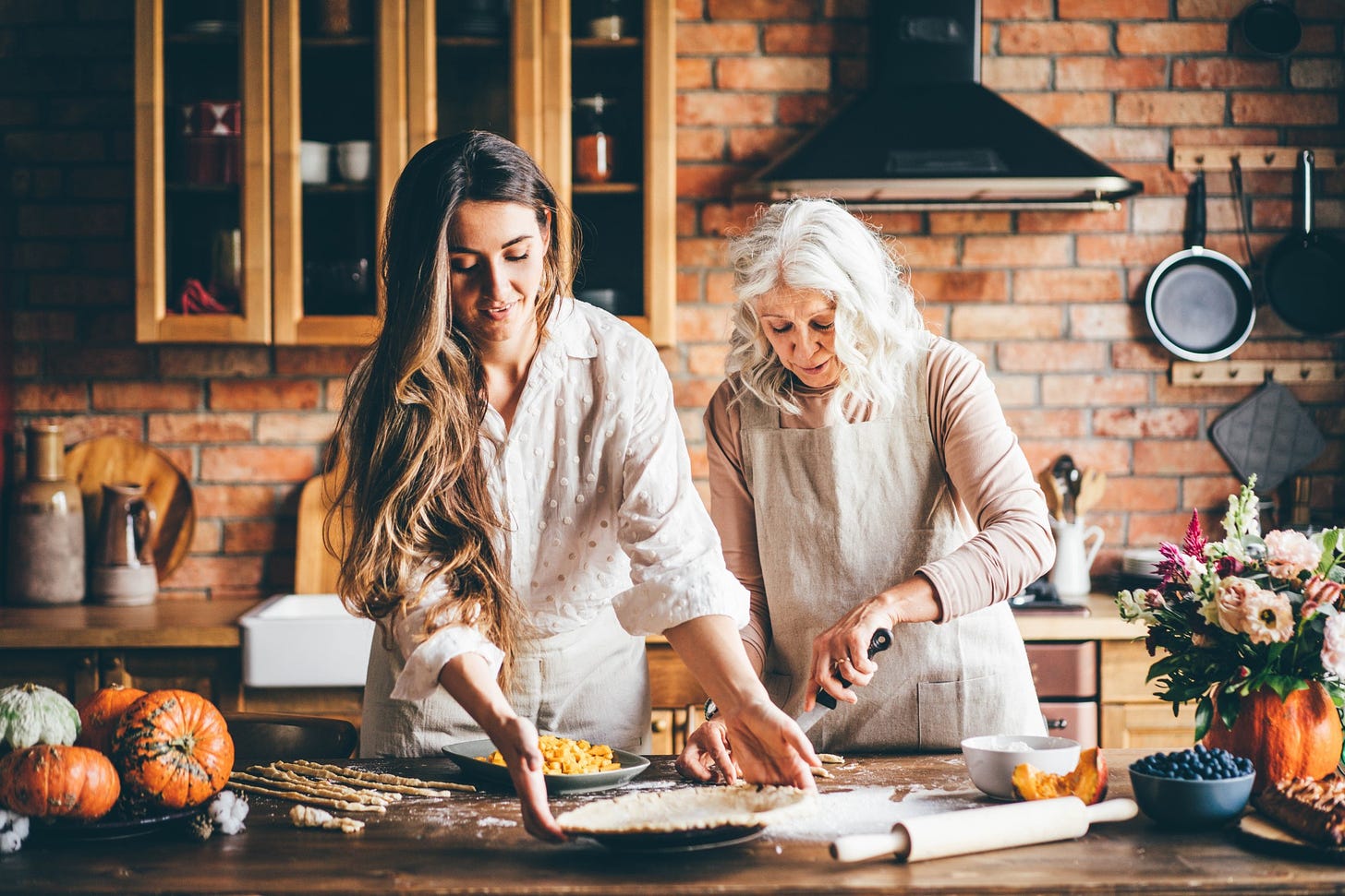 A woman and her aging mother bake together in a kitchen.