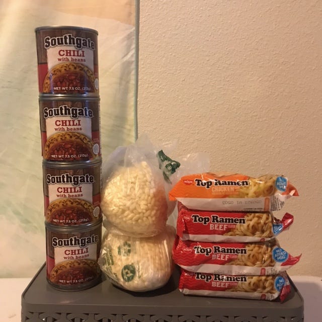 Four cans of chili, four bags of Top Ramen, and two produce bags full of loose Rice Krispies.