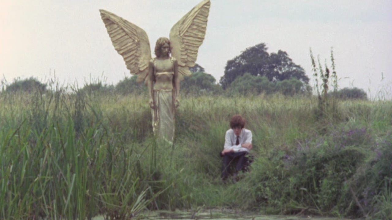 A boy sat in a green rural landscape with a golden jesus-angel figure stood behind him looking at him, ominously. 