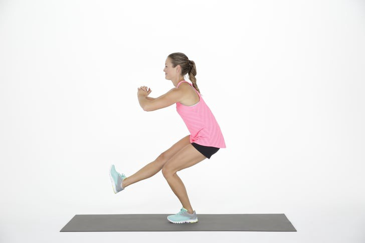 A side-view of a woman doing a single-leg quarter squat on a yoga mat