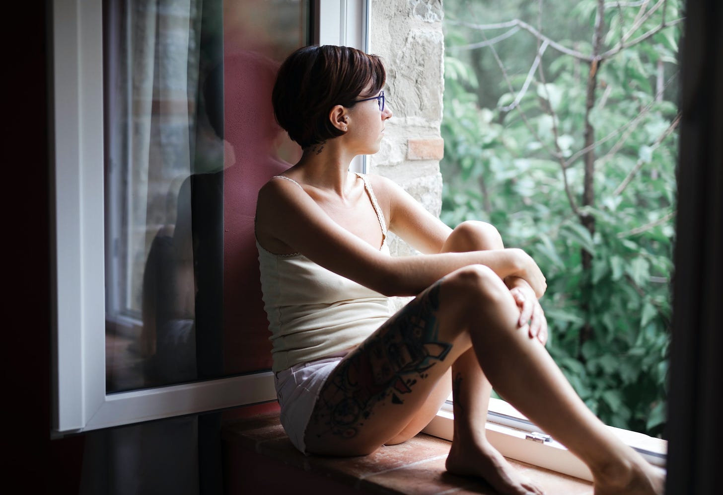 Woman in white tank sitting on window pane