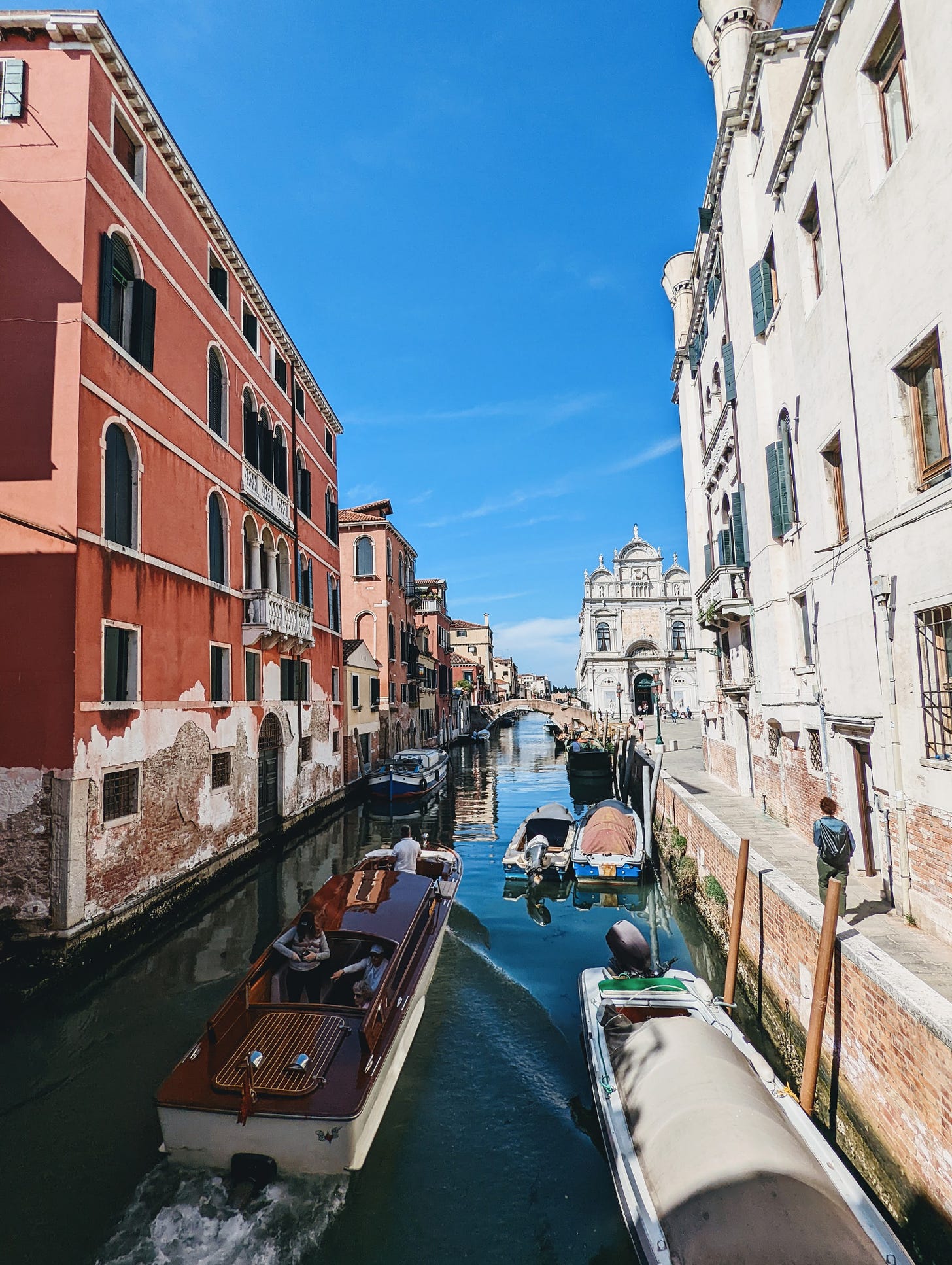 A canal in Venice, Italy during my first-ever trip to Europe. Blue skies hang over aged buildings and a narrow canal filled with small boats.