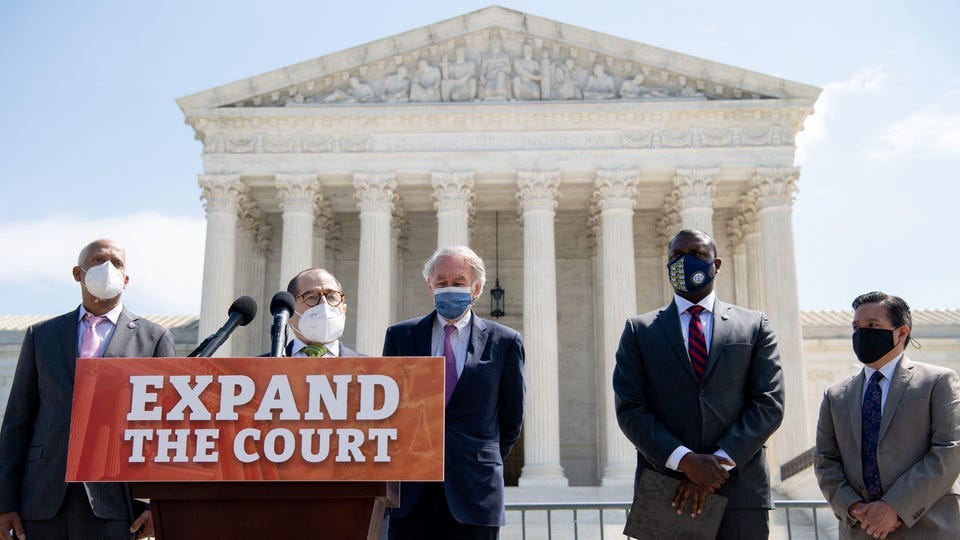 Lawmakers speak in front of U.S. Supreme Court building with Expand the Court sign on podium