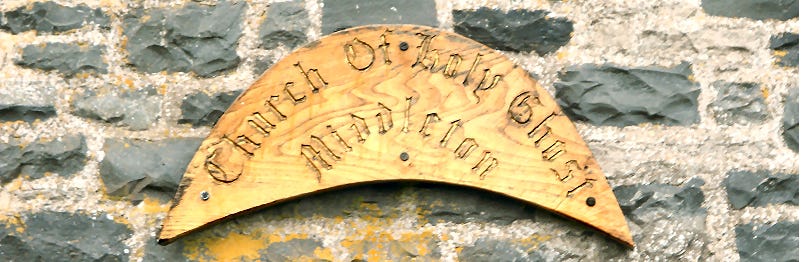 Crescent-shaped wooden plaque affixed to a stone wall, with "Church of Holy Ghost" carved on it.