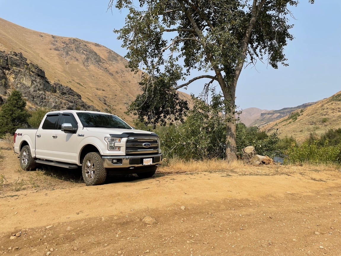 A white truck parked on a dirt road next to a tree

Description automatically generated with medium confidence