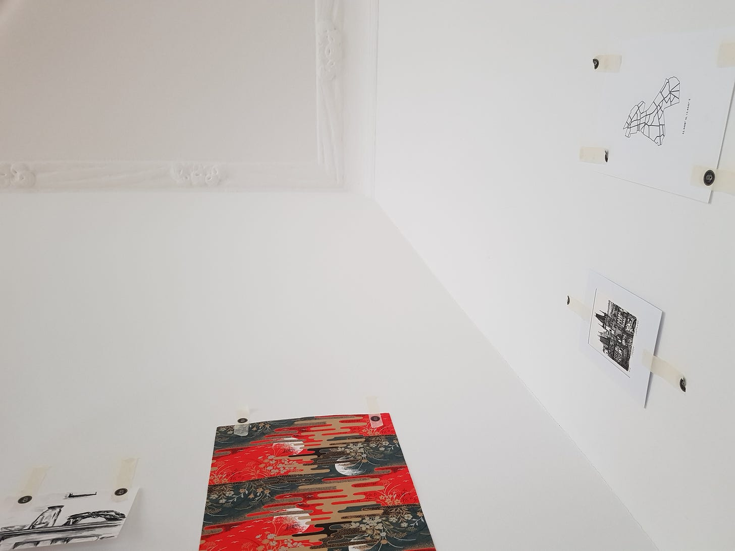 White walls and ceiling, with small pieces of artwork in black, white, and red.