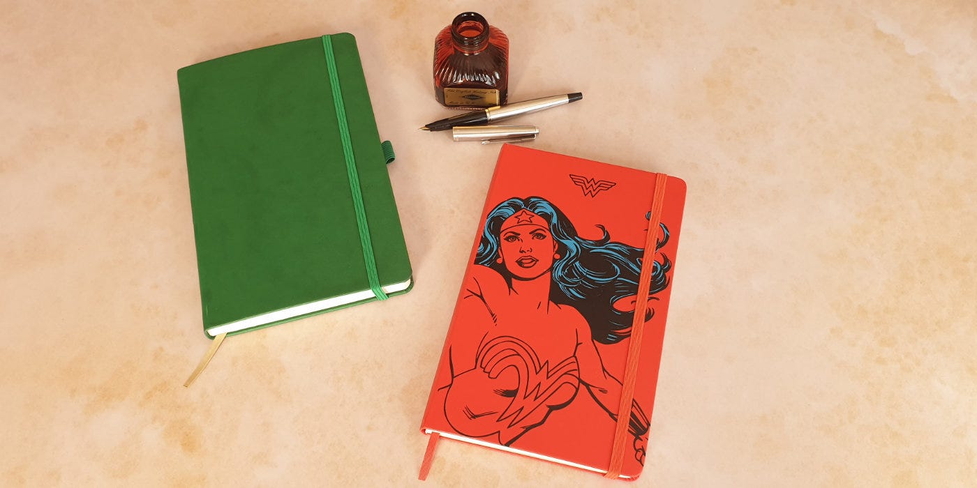 Two journals, one Castelli and one Moleskin and a bottle of red ink with a fountain pen