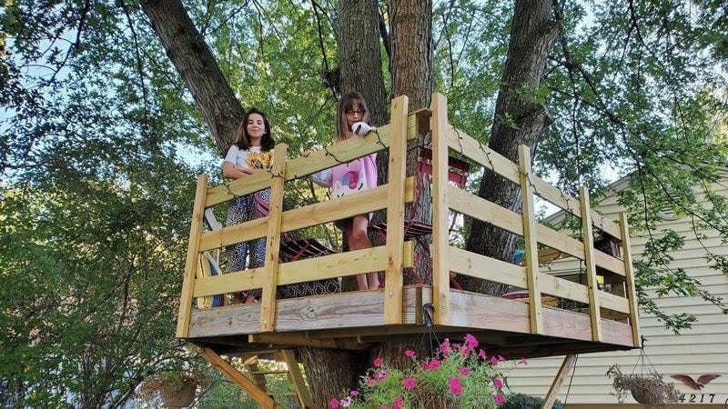 two girls standing in a treehouse