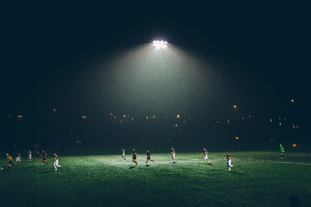 A night-time soccer match on a green pitch under the spotlights.