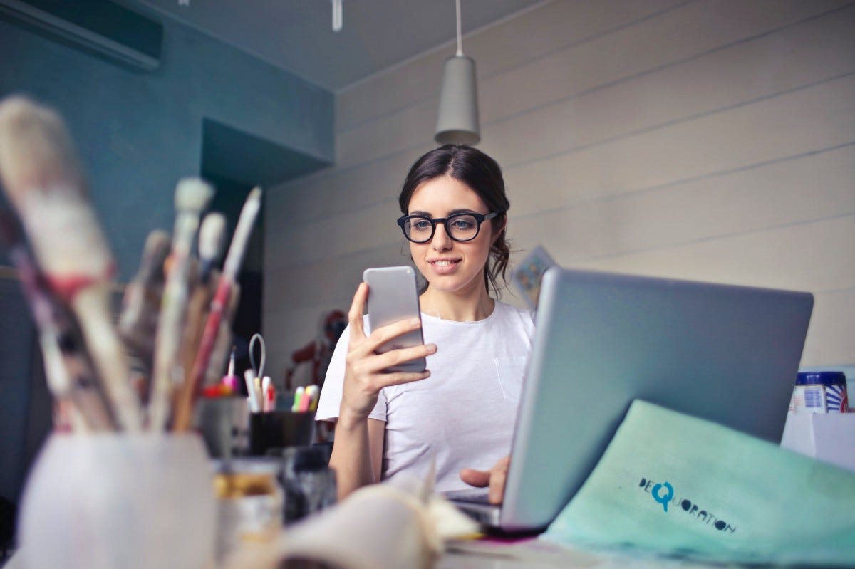 woman in white shirt using smartphone in an office
