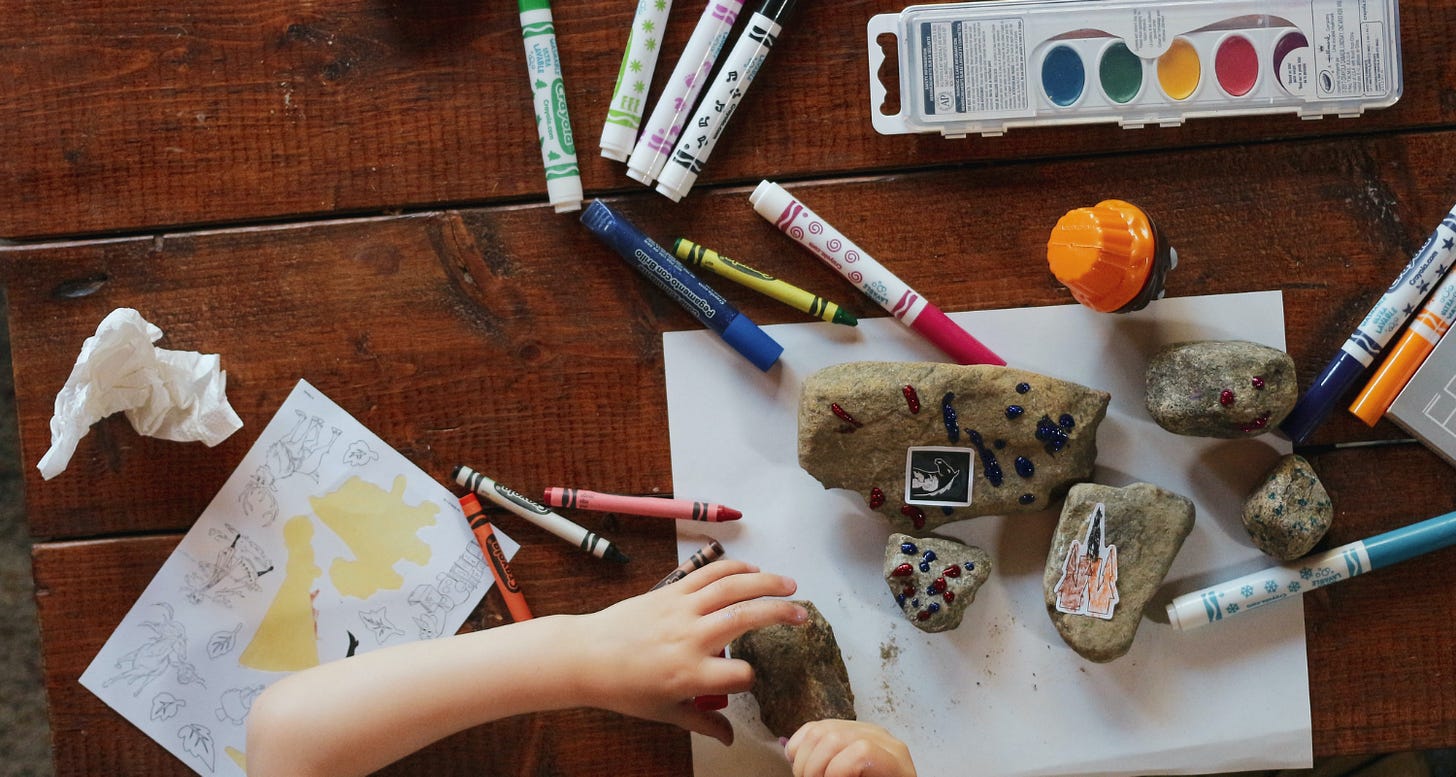 Overhead shot of a child drawing and painting at a wooden table
