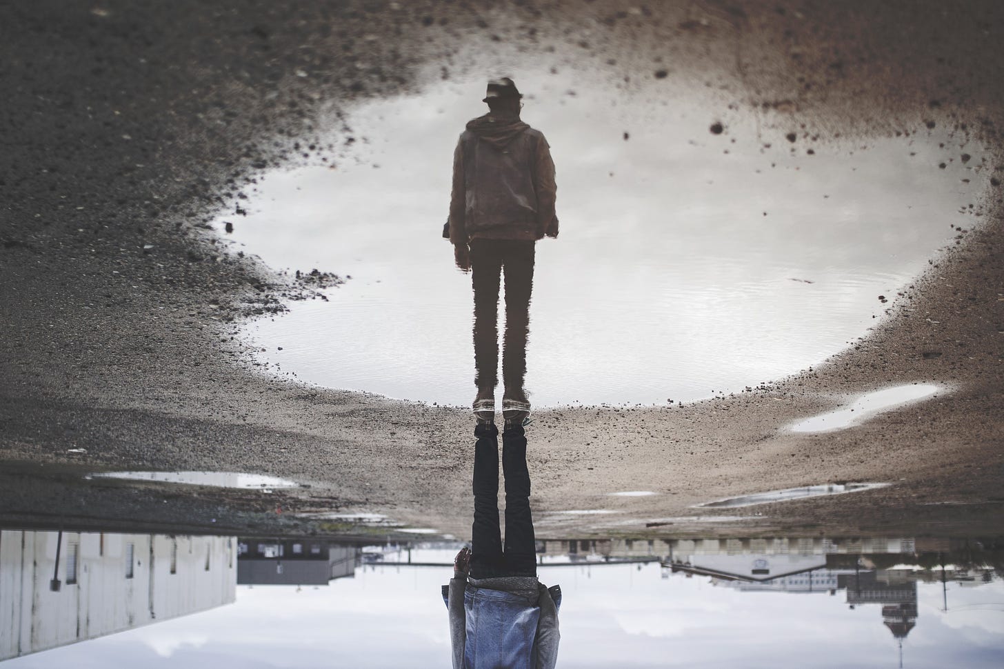 Image of a man’s reflection in a puddle for article by Larry G. Maguire