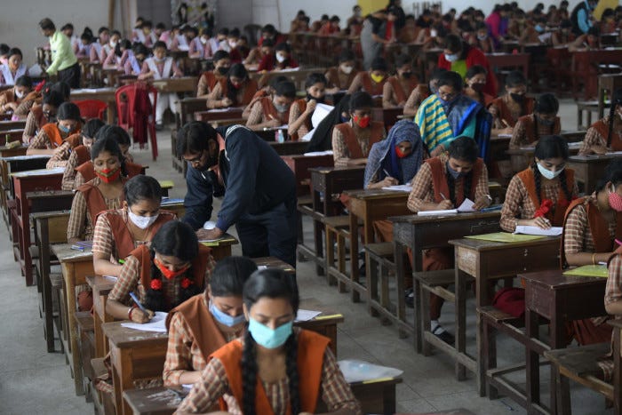 Rows of masked pupils sit in an exam hall 