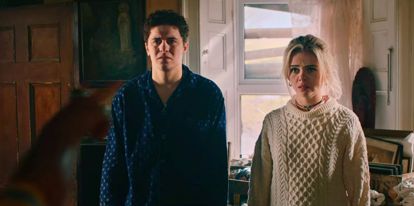 Dylan Llewellyn as James Maguire (left) and Saoirse-Monica Jackson as Erin Quinn (right) in DERRY GIRLS season 3. An out-of-focus hand is pointing at the duo.