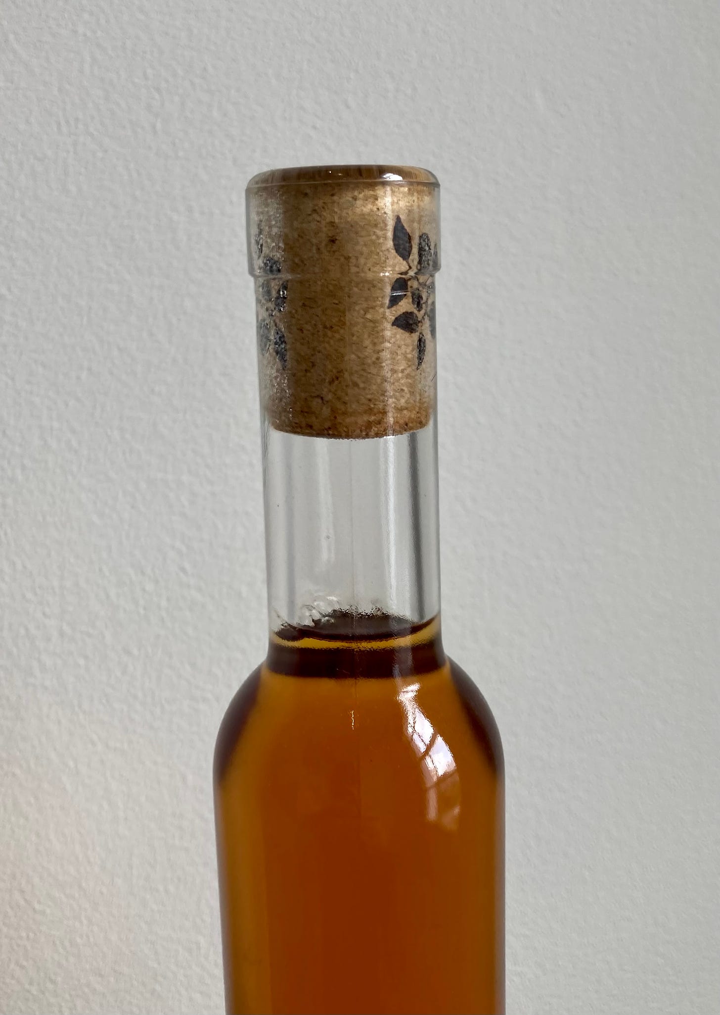 A bottle with a cork closure and no capsule, which shows a design added to the cork rather than on a capsule.