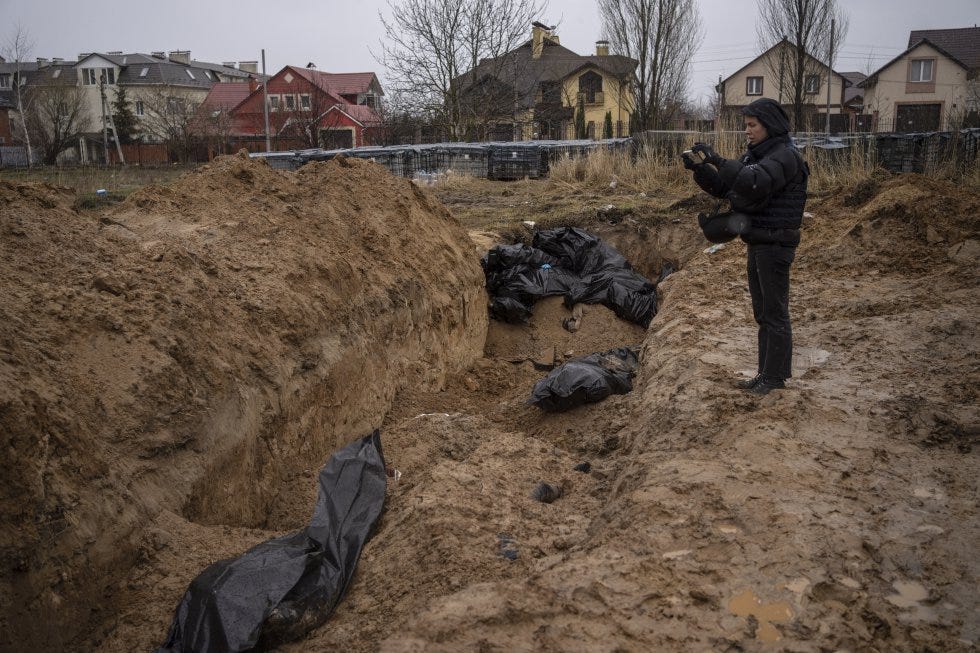 A journalist takes photos of a mass grave in Bucha on Sunday.