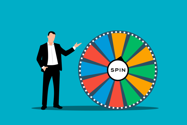 Man Standing Next to Prize Wheel. Image courtesy of Mohamed Hassan.