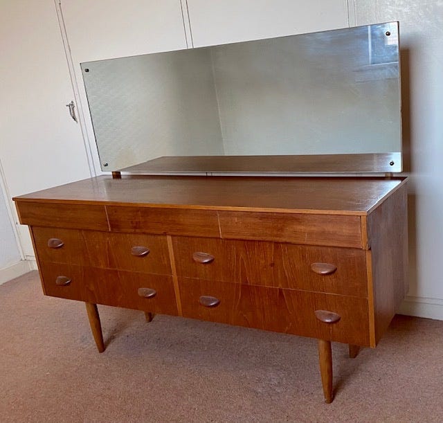 Beautiful mid-century modern dresser with subtle handles, four drawers, and a long mirror attached to the back.