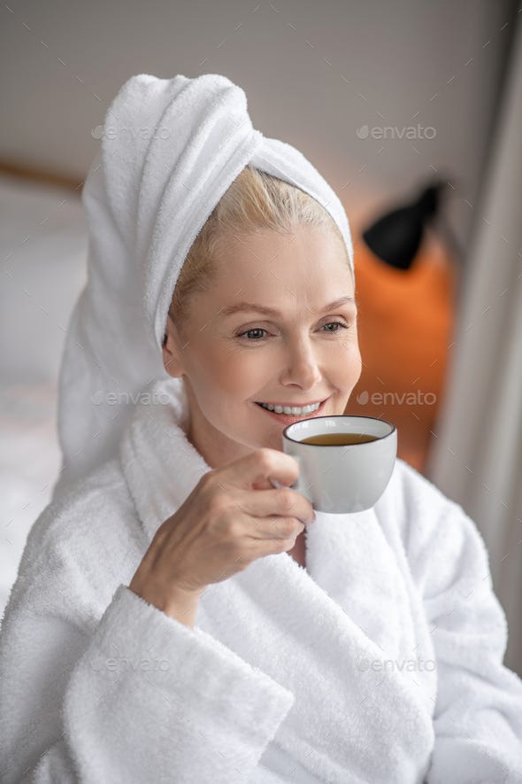 Beautiful woman in a white robe having coffee after the bath Stock Photo by  Zinkevych_D