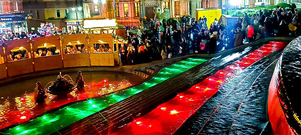 A fountain lit with Christmas colors.