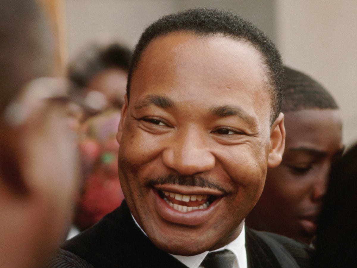 Martin Luther King Jr. tersenyum di antara masyarakat pendukungnya.