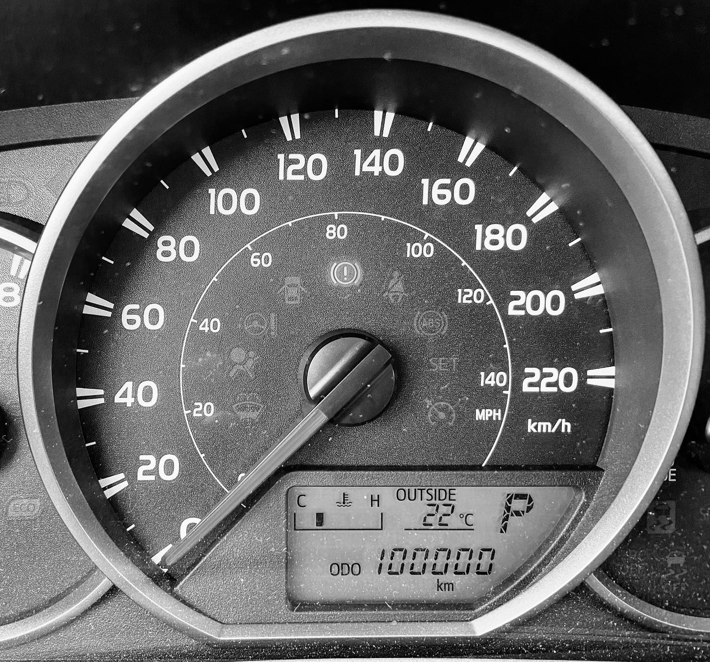 Car odometer in black and white photo showing 100000 km.