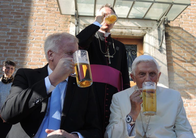 The retired Pope Benedict XVI (R) and the premier of the state of Bavaria, Horst Seehofer (CSU), drink a glass of beer in the Vatican Garden in Vatican City, 17 April 2017. Benedict's private secretary Georg Gaenswein stands behind the two. Benedict is celebrating his 90th birthday and received visitors from Bavaria, the German state from which he hails. His actual birthday was celebrated with a small circle of intimates including his older brother Georg, Gaenswein and his housekeeper. Photo by Lena Klimkeit/picture alliance via Getty Images
