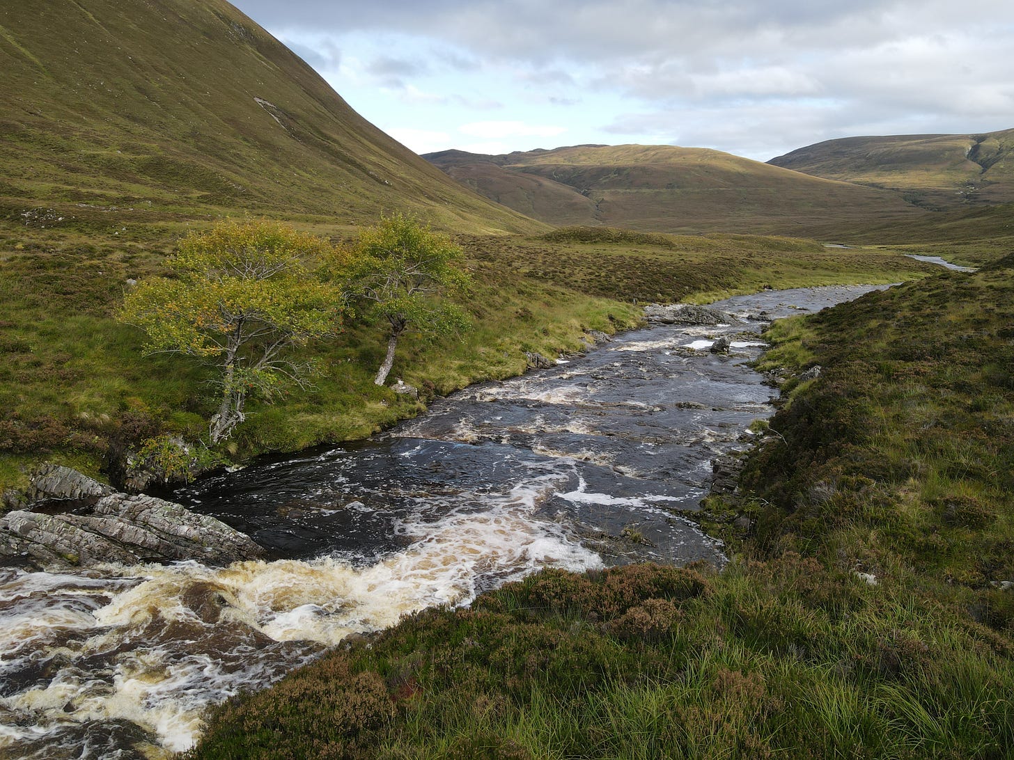 Landscape shot of a river surrounded by valleys in Scotland on a cloudy day