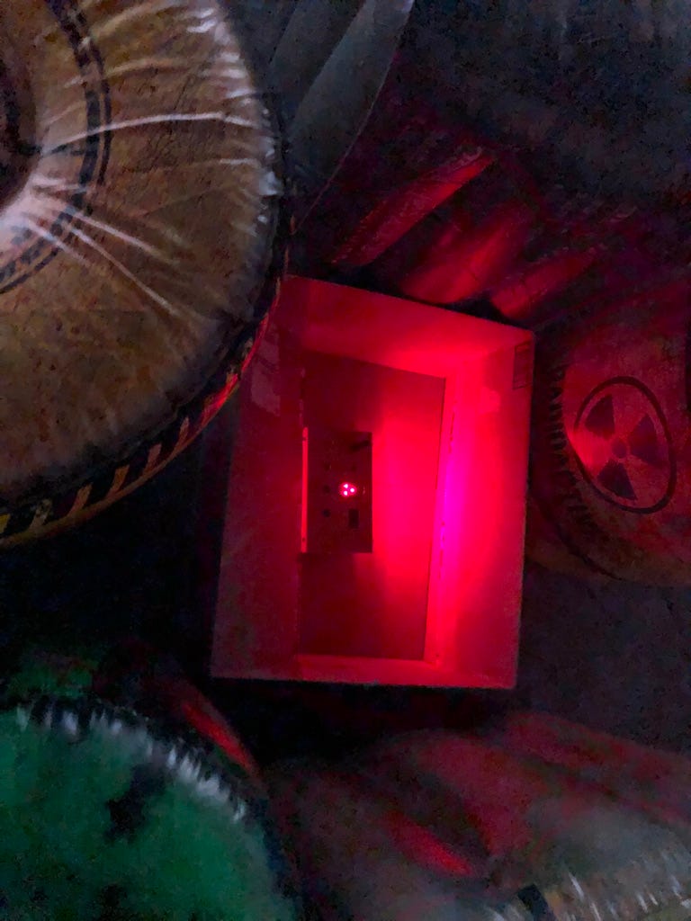 A glowing red box hidden in the center of foam terrain painted with radioactive iconography.