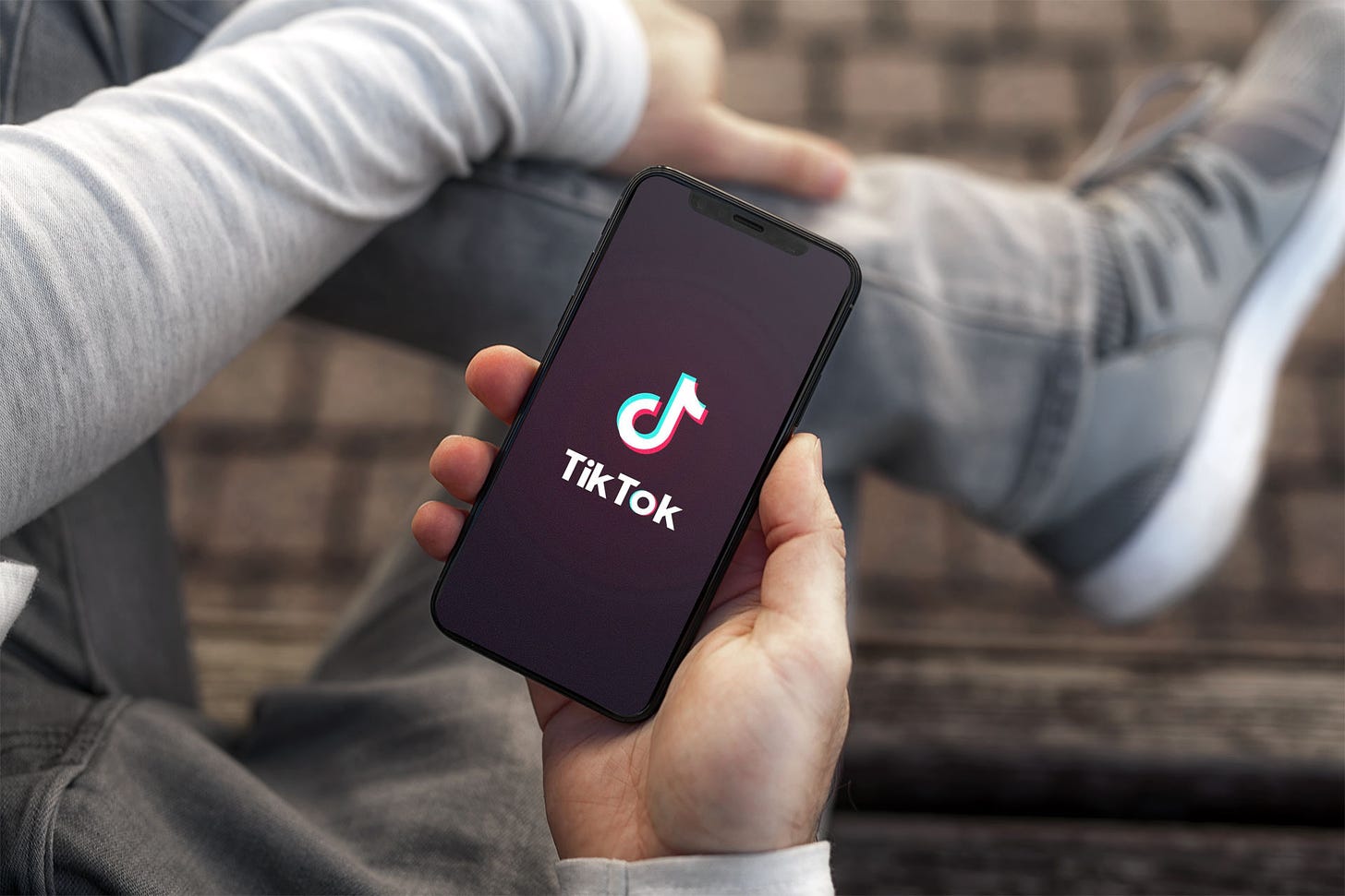 Person relaxing while loading TikTok on a smartphone