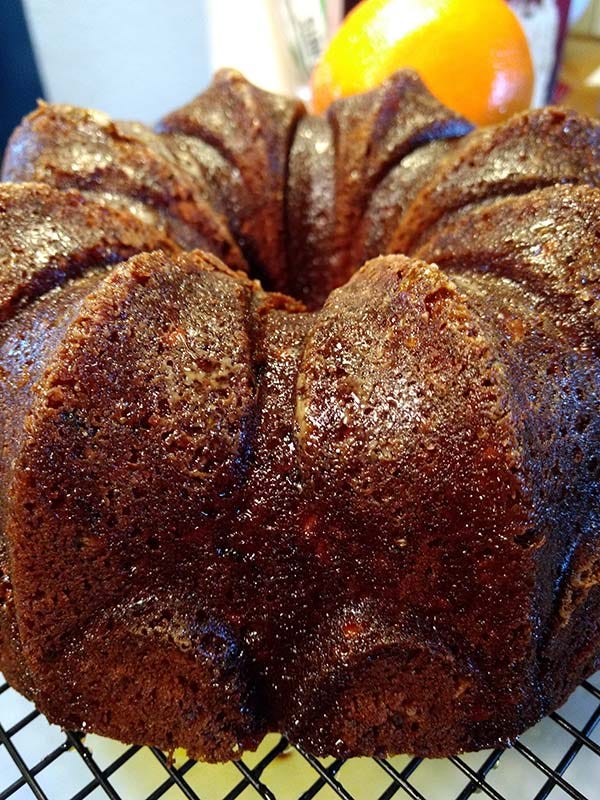 A closeup of the Orange Kiss Me Cake made in a bundt pan with an orange in the background.