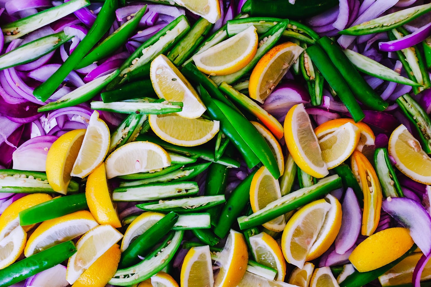 a tray full of colourful lemon wedges, jalepenos, and red onions