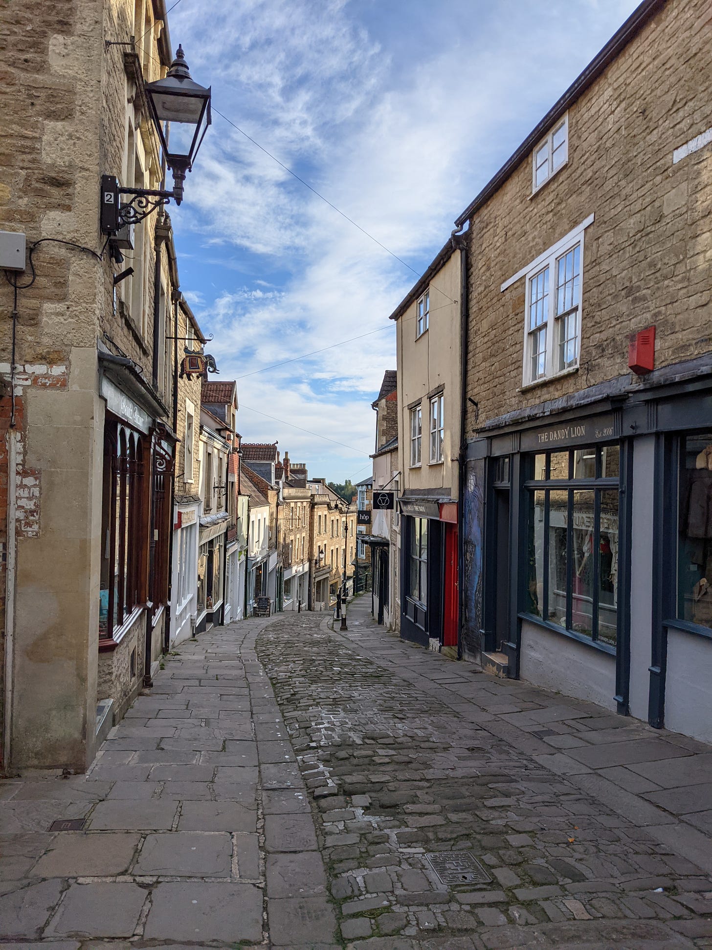 A view down Catherine Hill, a cobbled street lined with shops, in Frome, Somerset