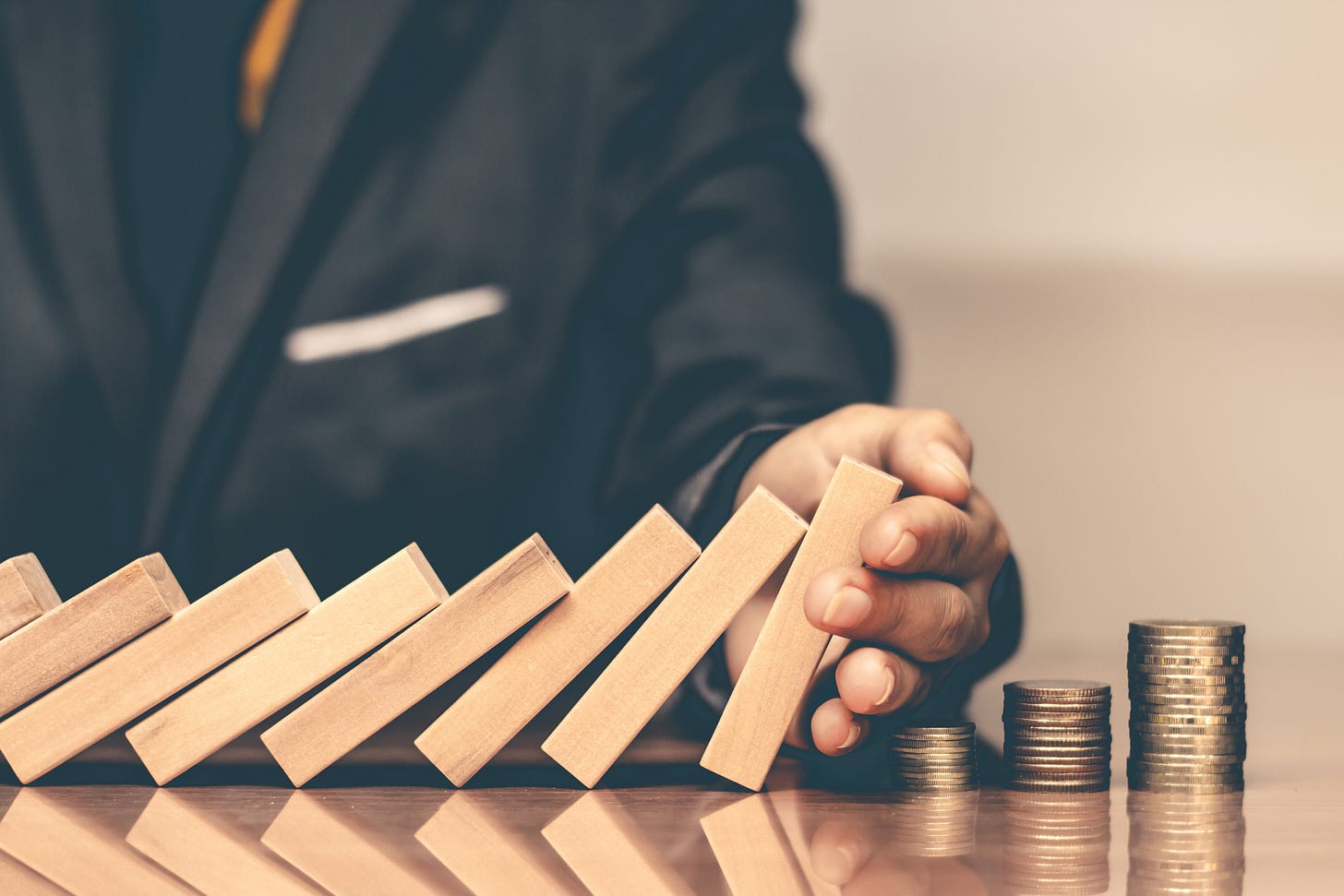 Midsection Of Businessman Holding Toy Blocks With Coins At Desk