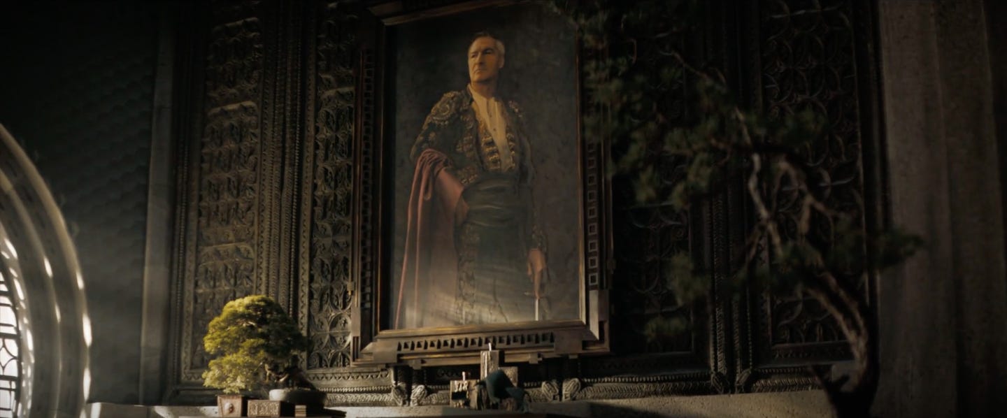 Image description: A screenshot of the new film Dune, showing a mantle above a fireplace with an old painted portrait flanked by traditional bonsai designs. End image description.