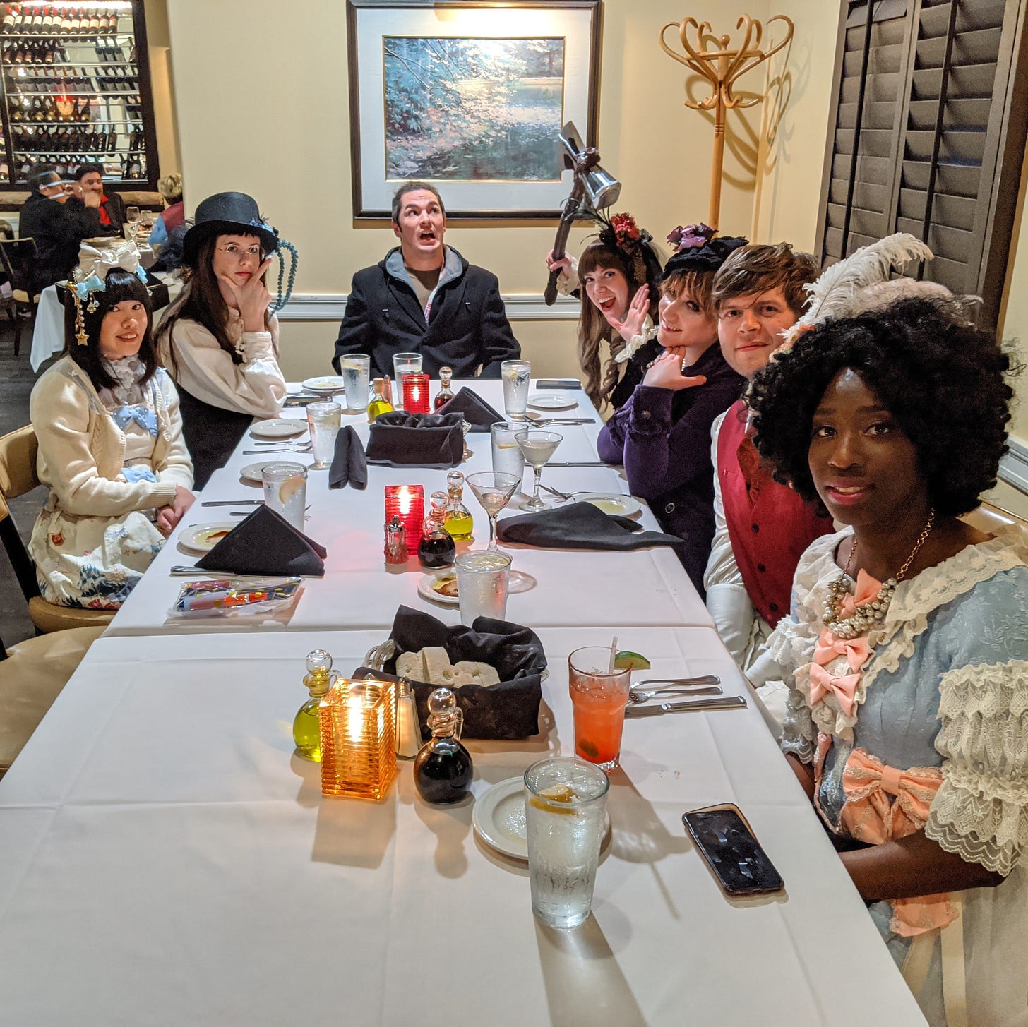A group of Lolitas and their partners sitting around a dinner table, wearing various OTT and Ouji looks. They are smiling at the camera and goofing off.