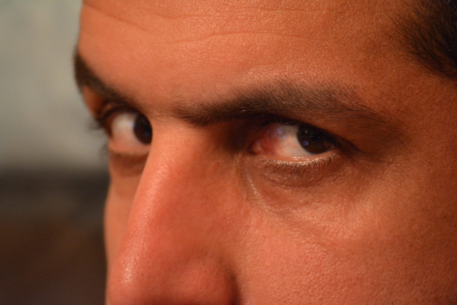 A man’s angry eyes stare closely into the camera.