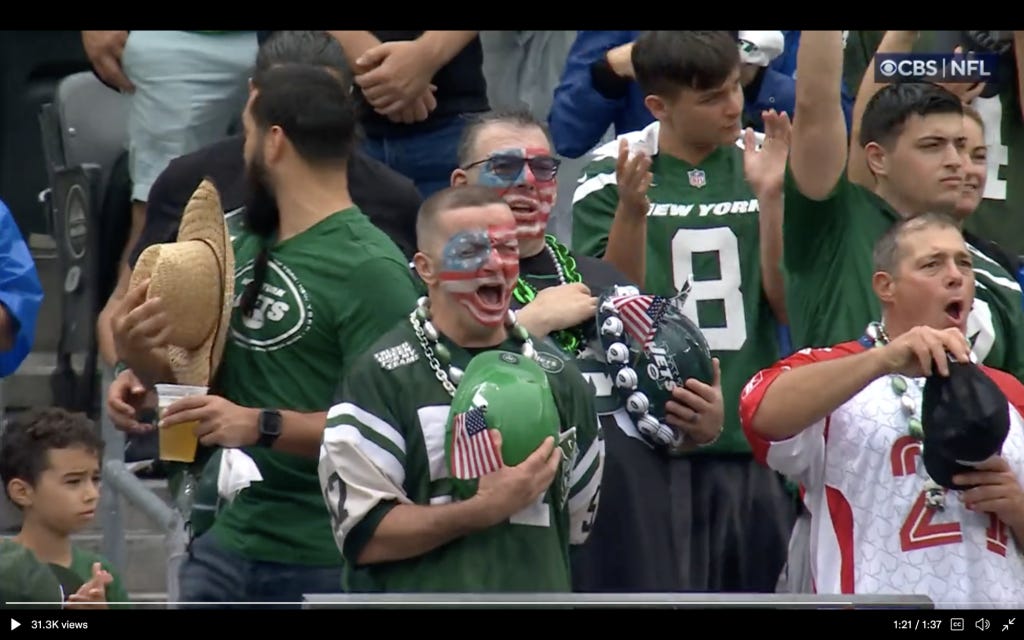 Jets fans sing the national anthem before a game against the Ravens.