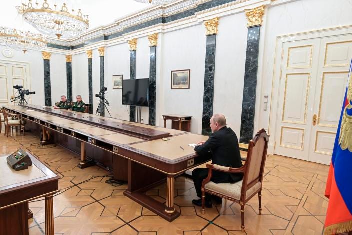 Russian President Vladimir Putin sits at one end of a long table with Russian Defense Minister Sergey Shoigu and Valery Gerasimov, head of the general staff of the armed forces, at the other.