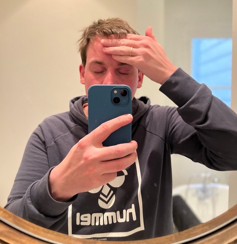 Mirror-selfie of Knut applying moisturiser to his forehead. 