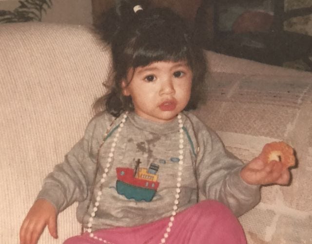 Baby Mia wearing a necklace, covered in drool, eating a cookie