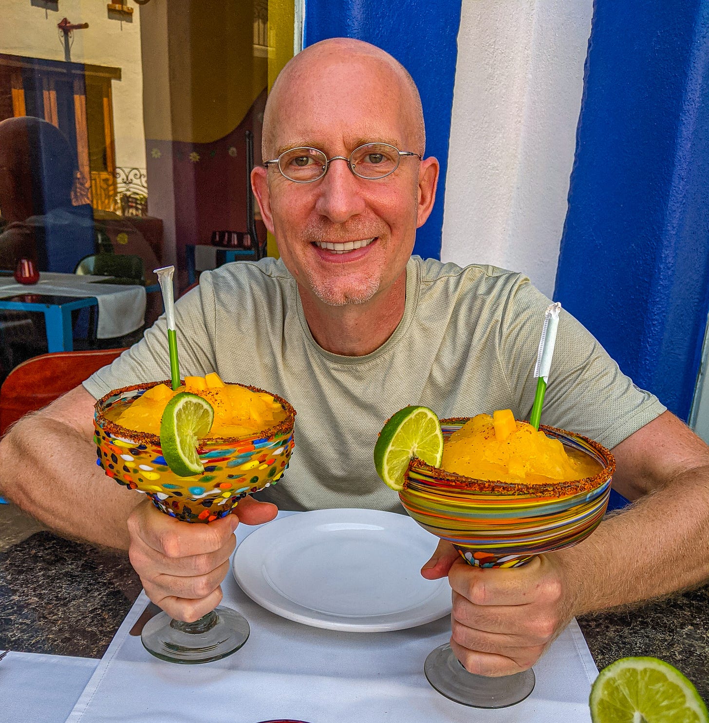 Brent at a restaurant in Mexico holding two delicious looking mango daiquiris. 