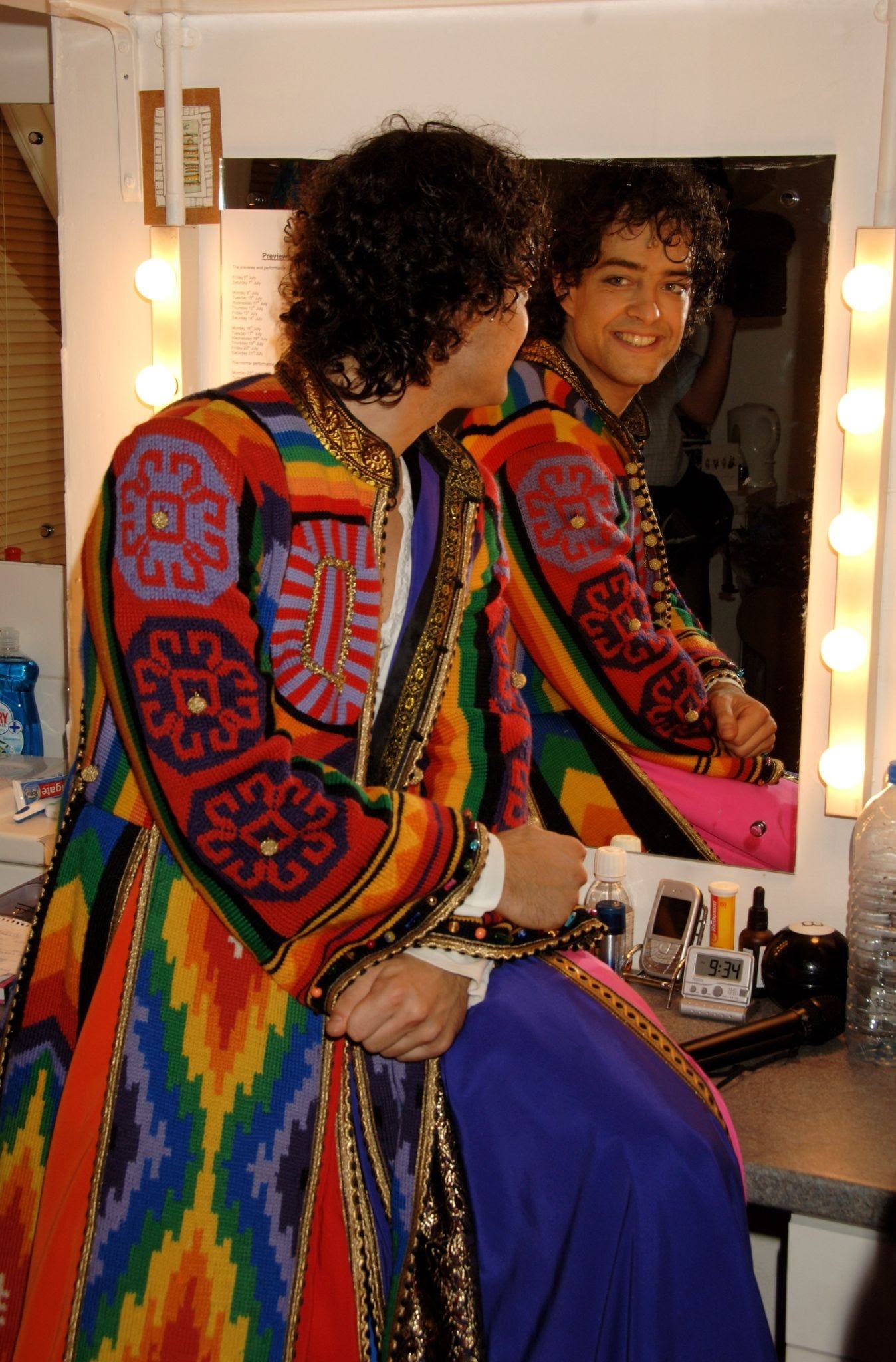 Photo of an actor from Joseph and the Amazing Technicolor Dreamcoat, with curly hair, looking at himself in the mirror, apparently enjoying the view